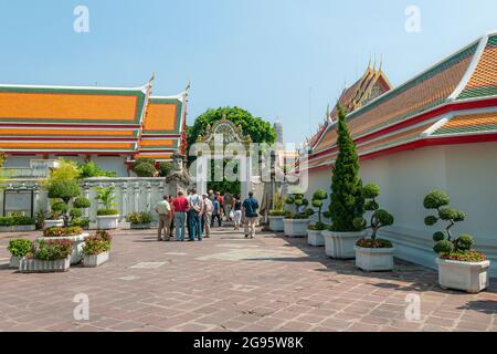 Touristes entrant dans une porte gardée par de grandes statues imposantes du gardien de Farang dans le complexe du temple Wat Pho Wat po à Bangkok en Thaïlande dans le sud-est A Banque D'Images