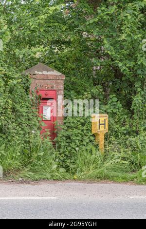 Poste rural peint en rouge ou boîte postale dans la ville de Cornish de Lostwithiel, à côté d'une borne incendie peinte en jaune. Pour les services postaux ruraux du Royaume-Uni, Fire Services Banque D'Images