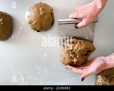 Baker cuit du pain de seigle crème anglaise avec des canneberges sur une surface de travail grise Banque D'Images