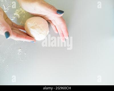 Une femme roule la pâte pour faire cuire du pain Banque D'Images