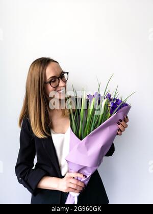 femme d'affaires avec un sourire ouvert dans des verres tient un bouquet de fleurs Banque D'Images