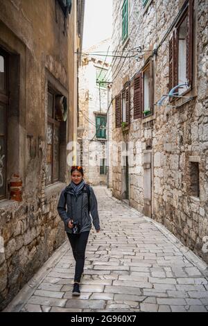 Femme marchant dans une allée de pierre de galet à Sibenik Banque D'Images