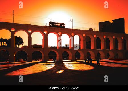 Vue spectaculaire de l'emblématique tramway Santa Teresa qui longe l'aqueduc Carioca au coucher du soleil dans le centre-ville de Rio de Janeiro, au Brésil Banque D'Images
