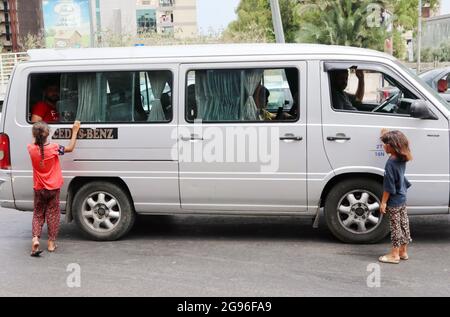 Beyrouth, Liban. 23 juillet 2021. Une fourgonnette à passagers partagés est entourée de mendiants syriens à Beyrouth, au Liban, le 23 juillet 2021.selon le site Internet d'Al Jazeera, « les pénuries de carburant et la hausse du prix de l'essence menacent de mettre un terme au système de transport public libanais ». (ELISA Gestri/Sipa USA) Credit: SIPA USA/Alay Live News Banque D'Images