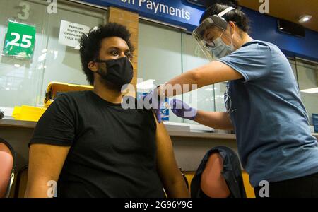 Toronto, Canada. 24 juillet 2021. Le 24 juillet 2021, un homme portant un masque facial reçoit une dose du vaccin COVID-19 dans une clinique de vaccination à Mel Lastman Square, à Toronto, au Canada. La ville de Toronto a ouvert une clinique de vaccination d'une durée d'un week-end ici samedi, accueillant des personnes sans rendez-vous chez les personnes âgées de 12 ans et plus pour la vaccination contre le COVID-19. Credit: Zou Zheng/Xinhua/Alamy Live News Banque D'Images