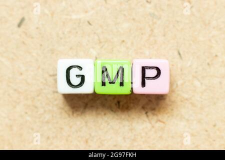 Bloc alphabétique de couleur dans le mot GMP (Abréviation de bonne pratique de fabrication) sur fond de bois Banque D'Images