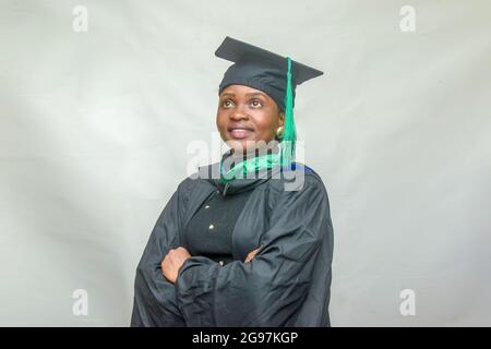 Portrait d'une femme africaine heureuse finissant ou finissant des étudiants souriant dans sa tenue noire Banque D'Images