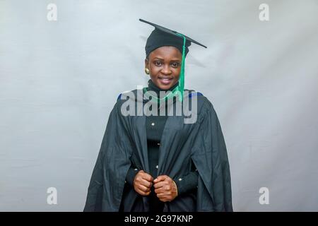Portrait d'une femme africaine heureuse finissant ou finissant des étudiants souriant dans sa tenue noire Banque D'Images