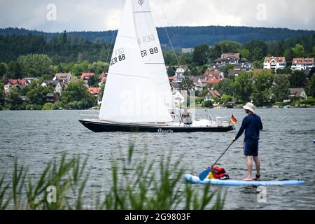 Insel Reichenau im Bodensee, Allemagne. 11 juillet 2021. Un bateau naviguant sur le lac de Gnaden entre l'île de Reichenau et Allensbach, tandis que dans le premier plan un homme passe un stand-up paddle board. Le lac de Constance est une destination populaire pour les vacanciers. (À dpa 'Association: Plus d'un milliard d'euros de dette corona dans l'industrie de l'hôtellerie') crédit: Felix Kästle/dpa/Alay Live News Banque D'Images