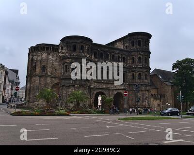 Vue sur la porte historique de la ville romaine 'Porta Nigra' (latin : porte noire) avec façade en pierre noire décolorée dans le centre de Trèves avec rue et touristes. Banque D'Images