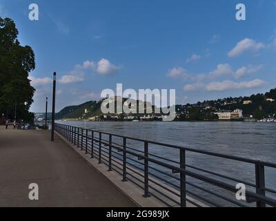 Promenade inondée au bord de la rivière dans la ville de Koblenz avec le Rhin au niveau de l'eau élevé le jour ensoleillé d'été avec la forteresse de main-d'eau en métal Ehrenbreitenstein. Banque D'Images