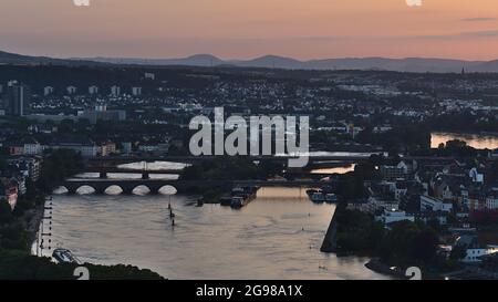 Belle vue aérienne sur la ville de Koblenz au coucher du soleil avec la Moselle, les ponts Balduinsbrücke et Europabrücke et le ciel orange au-dessus des collines à l'horizon. Banque D'Images