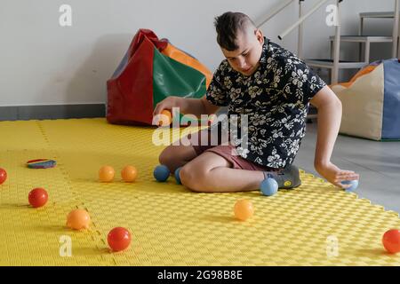 Les enfants ayant un handicap se font une activité sensorielle avec des jouets, des balles, des petits objets, un garçon souffrant de paralysie cérébrale jouant à un jeu apaisant, s'entraîner à de fines aptitudes motrices Banque D'Images