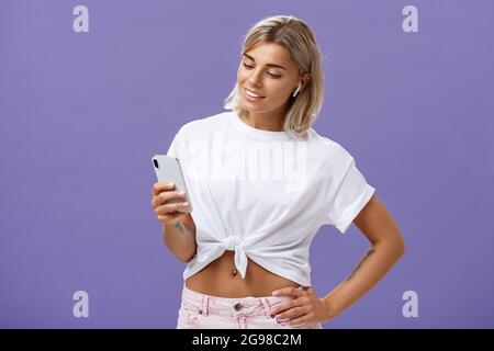 Découvrez le nouveau morceau de votre chanteur préféré. Femme européenne au look sociable et insouciante avec une musique à la peau bronzée dans des écouteurs sans fil Banque D'Images