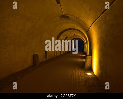 Perspective décroissante du tunnel dans le château historique construit au XVIe siècle avec des murs illuminés par la lumière jaune et sortie à Koblenz, Allemagne. Banque D'Images