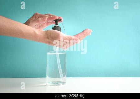 Femme mains utilisant le distributeur de pompe de désinfectant liquide pour les mains. Gros plan, mise au point sélectionnée. Banque D'Images