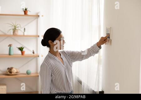 Femme indienne souriante utilisant un système de maison intelligent, une manette Banque D'Images