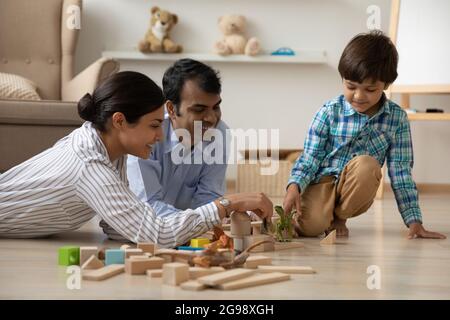 Une jeune famille indienne heureuse avec un petit fils jouant sur le sol Banque D'Images