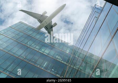 Avion survolant un immeuble de bureaux moderne. Façade extérieure du bâtiment gratte-ciel. Voyage d'affaires. Réflexion dans des fenêtres en verre transparent. Aviation Banque D'Images