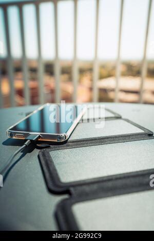 Charger un smartphone depuis la maison avec un chargeur portable pour panneau solaire. Banque D'Images