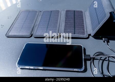Charger un smartphone depuis la maison avec un chargeur portable pour panneau solaire. Banque D'Images