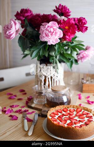 délicieux et délicieux petit déjeuner. cheesecake aux fraises sur fond de bois avec un bouquet de pivoines Banque D'Images