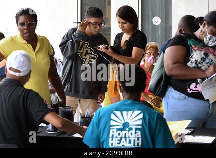 Les gens s'inscrivent pour recevoir une photo lors d'un événement de vaccination mobile COVID-19 au campus du centre-ville d'Orlando de l'Université de Floride centrale et du Collège de Valence. La Floride est le chef de file de la nation dans les nouveaux cas de coronavirus à mesure que les hospitalisations se sont envolée. Banque D'Images