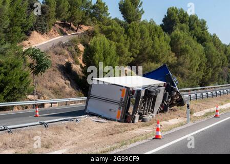 Camion avec semi-remorque réfrigérée en cas d'accident, renversé par la sortie de l'autoroute au milieu de l'autoroute. Banque D'Images