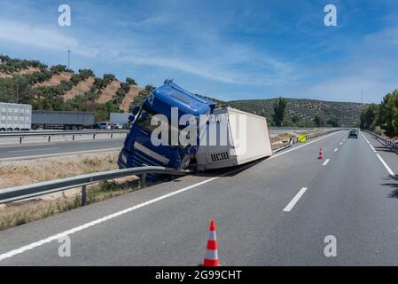 Camion avec semi-remorque réfrigérée en cas d'accident, renversé par la sortie de l'autoroute au milieu de l'autoroute. Banque D'Images