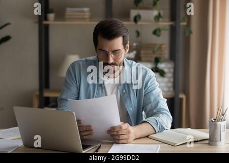 Un homme d'affaires sérieux lisant un contrat assis au bureau du lieu de travail Banque D'Images