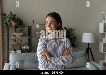 Femme debout dans une pièce moderne avec les bras croisés regardant loin Banque D'Images