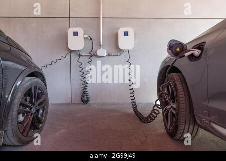 les voitures électriques sont facturées à un poste mural dans le garage Banque D'Images