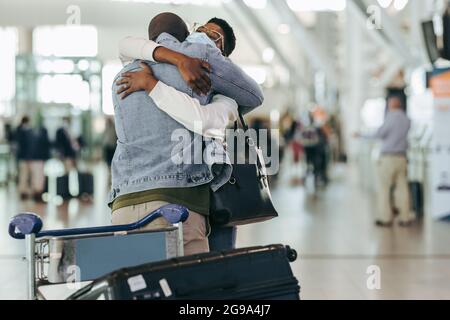 Un couple africain s'est réuni à l'aéroport après sa séparation en raison d'un covid. Homme et femme se embrassant à la porte d'arrivée du terminal de l'aéroport. Banque D'Images