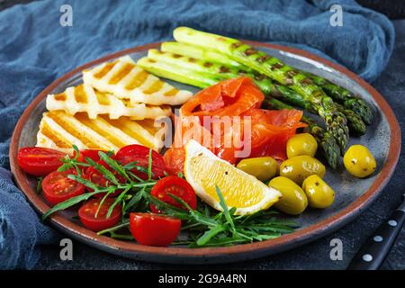 Salade aux asperges, fromage halloumi grillé, filet de saumon, tomates, arugula et olives vertes Banque D'Images