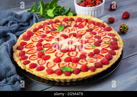 Délicieuse tarte maison aux fraises et aux framboises garnie de feuilles de menthe sur fond de bois Banque D'Images