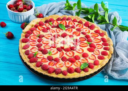 Délicieuse tarte maison aux fraises et aux framboises garnie de feuilles de menthe sur fond de bois Banque D'Images