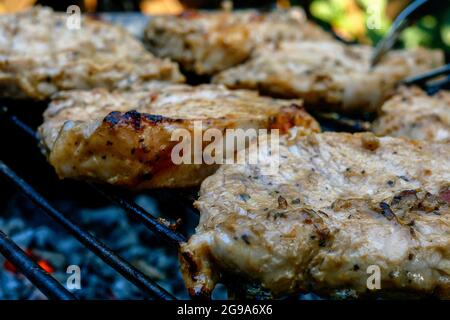 Friture de morceaux juteux de viande fraîche de steak de cou de porc préparée sur le grill ou le treillis de barbecue extérieur dans l'arrière-cour. Fumée sur charbon de bois. Gros plan. À l'extérieur. Banque D'Images