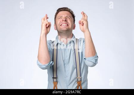 Jeune homme faisant un souhait isolé sur fond blanc Banque D'Images