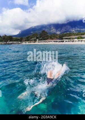 Un homme plonge en short plonge depuis une plate-forme vers la mer Banque D'Images