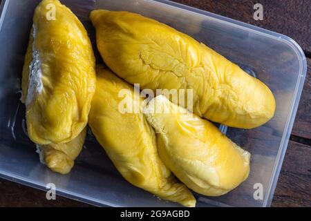 Vue rapprochée en hauteur de la chair de pâte de musang King durian jaune doré dans un récipient sur une surface en bois Banque D'Images