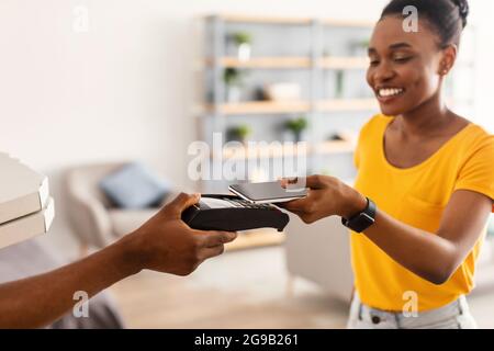 Happy Black Femme client payant Courier pour livraison de pizza intérieure Banque D'Images