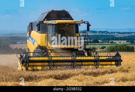 Byres Farm, East Lothian, Écosse, Royaume-Uni, 25 juillet 2021. Météo au Royaume-Uni: Récolte d'orge d'hiver: Le récent temps sec a permis à un agriculteur de commencer tôt la récolte. Photo : une moissonneuse-batteuse New Holland au travail Banque D'Images