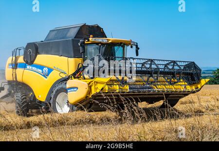 Byres Farm, East Lothian, Écosse, Royaume-Uni, 25 juillet 2021. Météo au Royaume-Uni: Récolte d'orge d'hiver: Le récent temps sec a permis à un agriculteur de commencer tôt la récolte. Photo : une moissonneuse-batteuse New Holland au travail Banque D'Images