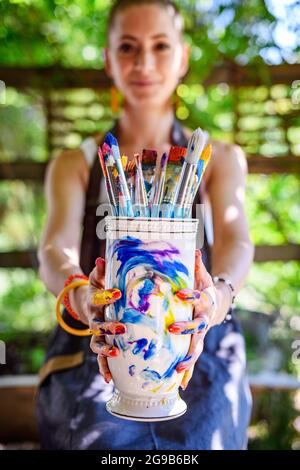 Jeune artiste peintre féminine tenant un tas de pinceaux usagés sales. Style de vie funky créativité hobbies fond. Banque D'Images