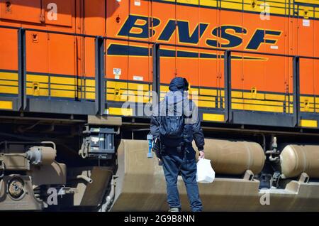 Berwyn, Illinois, États-Unis. Un homme nain par une locomotive qui passe attend sur une plate-forme qu'un train passe avant de traverser les voies ferrées. Banque D'Images