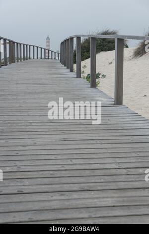 Passerelles en bois le long des dunes de la plage de Barra avec le phare d'Aveiro en arrière-plan en une journée nuageux. Portugal Banque D'Images