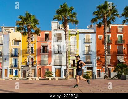 Coureur en face de maisons colorées en bord de mer, cases de couleurs, Carrer Arsenal, Villajoyosa, Espagne Banque D'Images