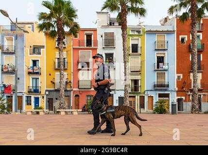 Policier avec chien devant des maisons colorées en bord de mer, cases de couleurs, Carrer Arsenal, Villajoyosa, Espagne Banque D'Images