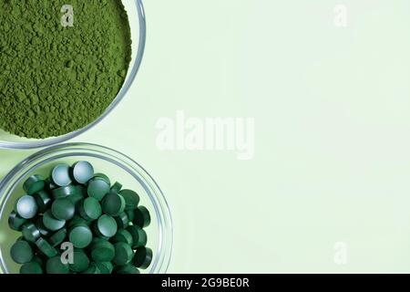 Pastilles de poudre de chlorelle et de spiruline sur fond vert. Supplément alimentaire biologique. Vue de dessus. Copier l'espace. Banque D'Images