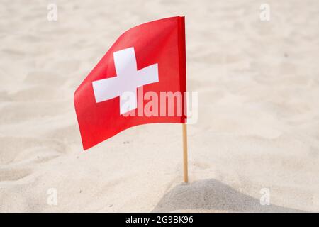 Drapeau de la Suisse sur fond de sable. Drapeau suisse agitant dans le vent sur la plage d'été Banque D'Images